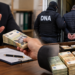 Inspector de la Fondul pentru Mediu, prins în flagrant când lua mită 45.000 de lei de la o firmă. Procurorii DNA au găsit aproape 90.000 de euro în locuința sa. A fost arestat preventiv